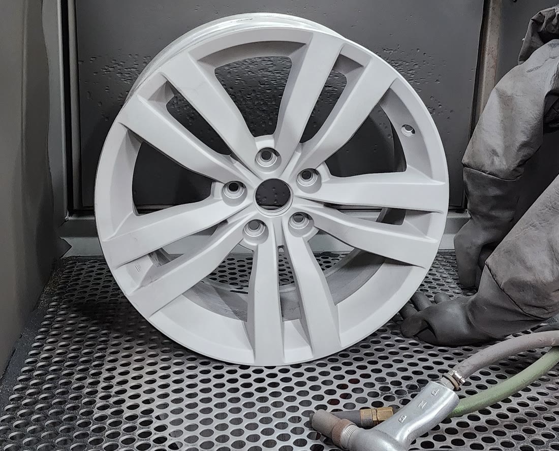 An alloy wheel blasted to bare metal in the blast cabinet at Cor Performance Coatings